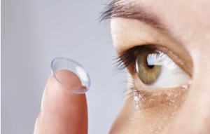 Up close image of someone in the action of inserting a contact lens into their eye.